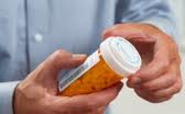 A person with a bottle of antibiotics in his hands.