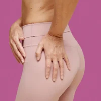 Woman in pink leggings, Brazilian butt lift surgeon questions article.