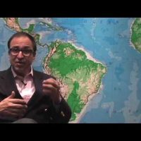 Dr. Ricardo L. Rodriguez sitting down in front of a world map.