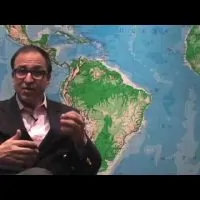 Dr. Ricardo L. Rodriguez sitting down in front of a world map.
