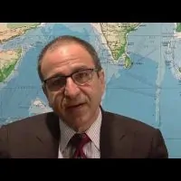 Dr. Ricardo L. Rodriguez sitting down in front of a world map.